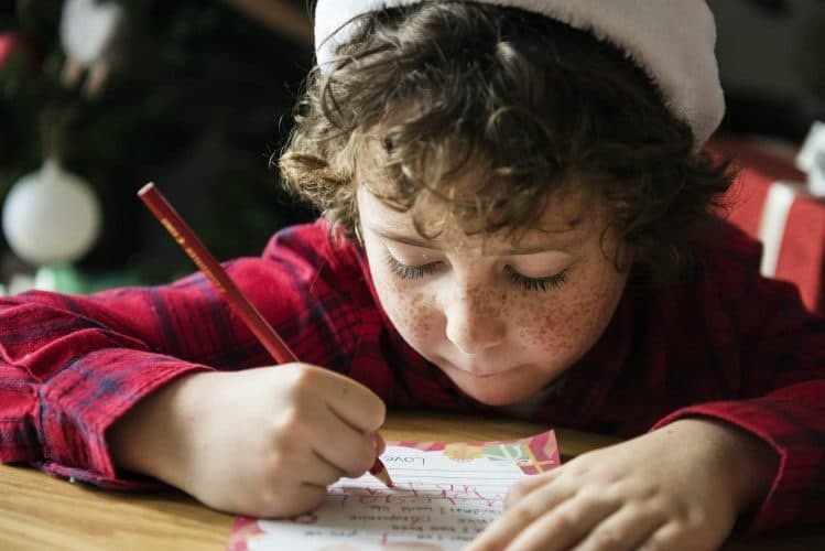 Caucasian kid writing a Christmas wishlist