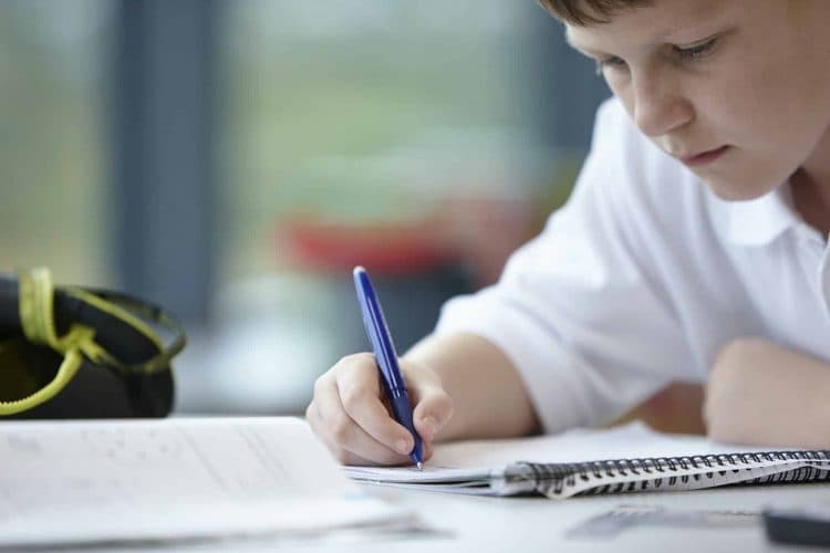 Close up of schoolboy writing in class