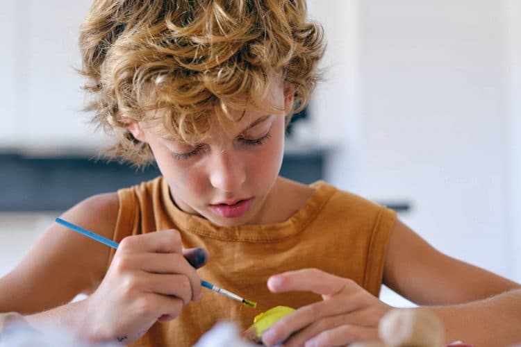 Focused child painting rock at home