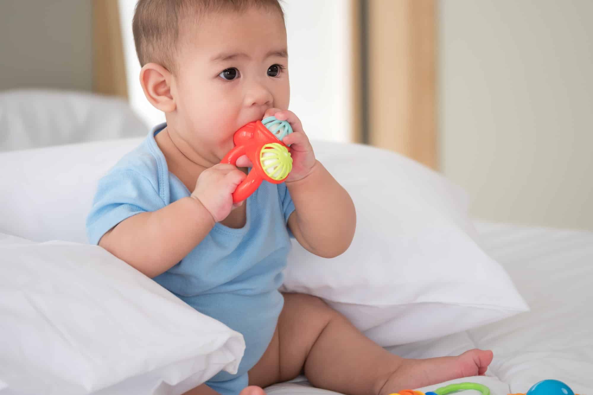 Cute newborn baby with toys in a bedroom.