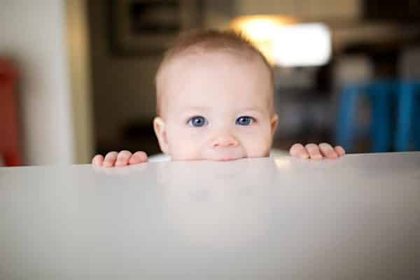 Little baby boy chewing on a white table