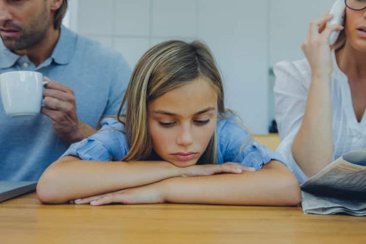 Frustrated girl with distracted parents at table