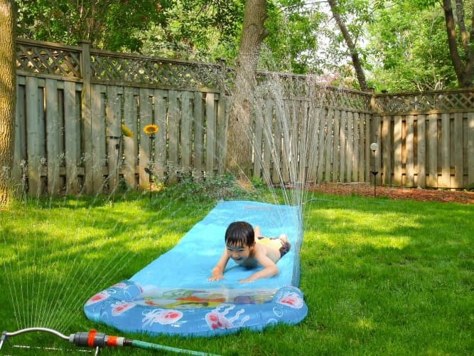 A Happy kid water play in a backyard in a Hot summer day