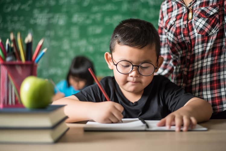 kid write a book in the classroom.