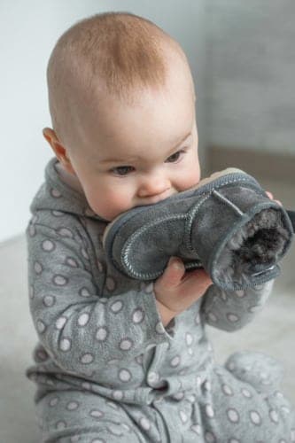 The kid chews on his shoe.