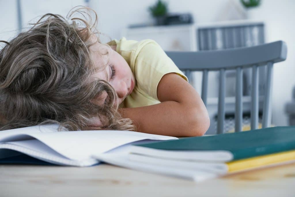 Close-up of a tired kid sleeping with his head rested on a table