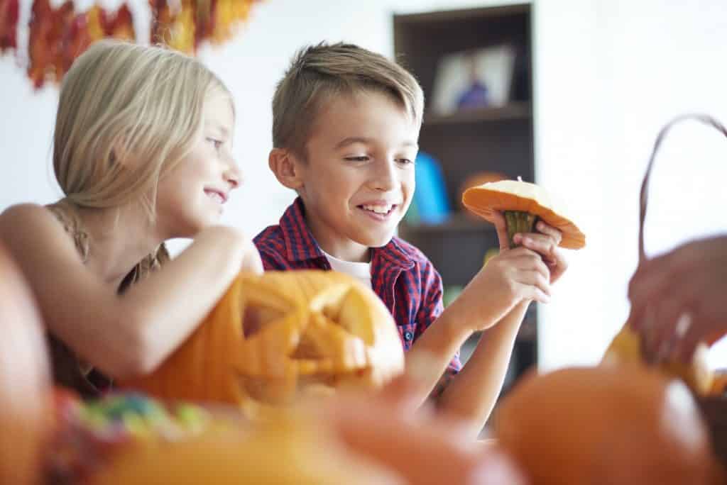 Cute siblings with Halloween pumpkins at home