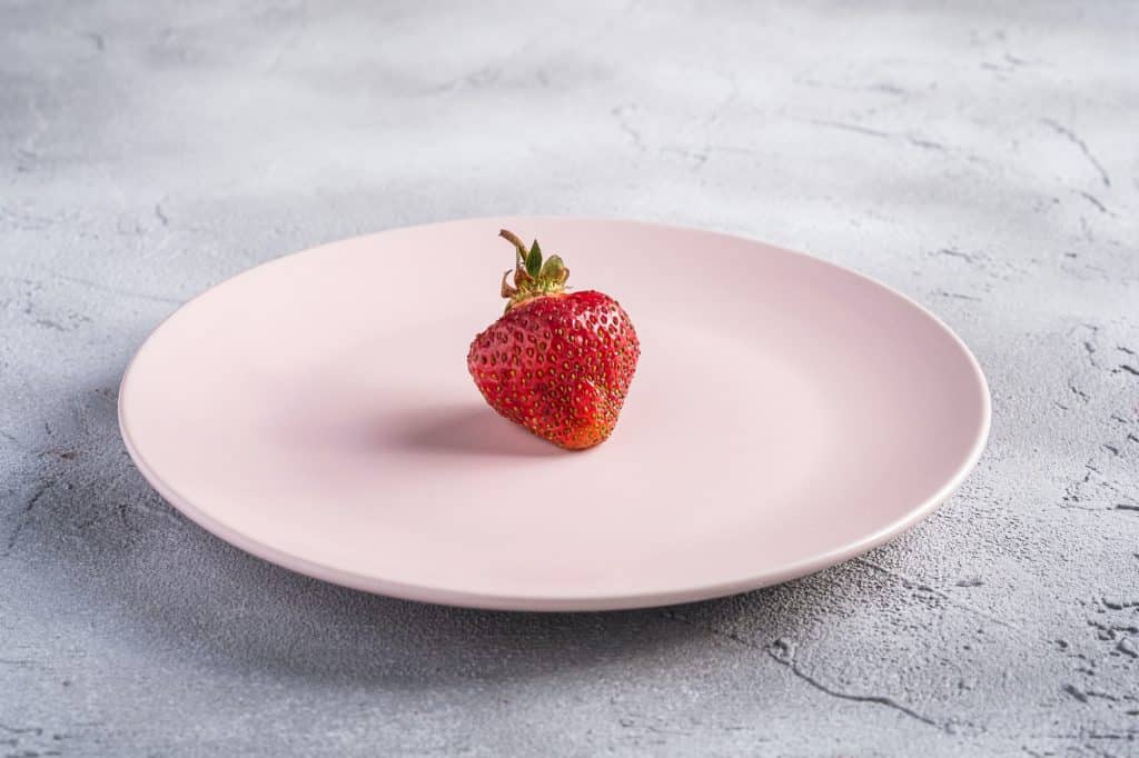 One fresh ripe strawberry fruit in pink plate