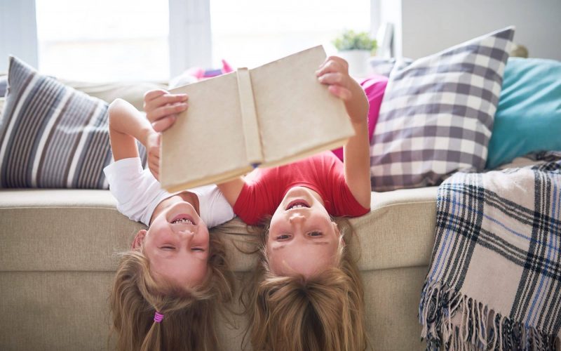 Sisters Reading Book Upside Down
