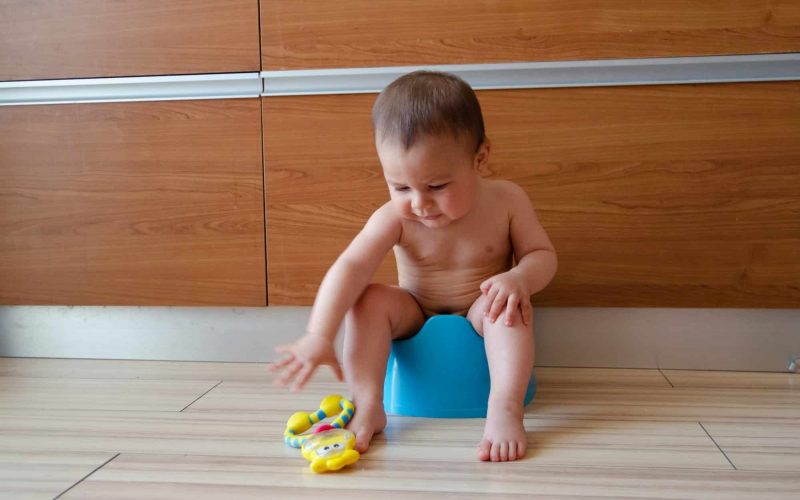 cute six months old baby boy sitting on the potty, potty training concept