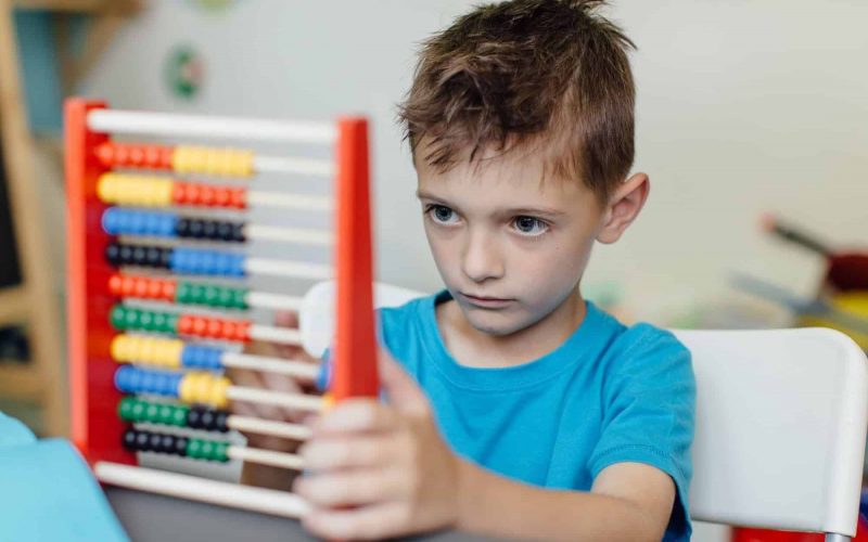 Focused schoolboy learning maths with an abacus
