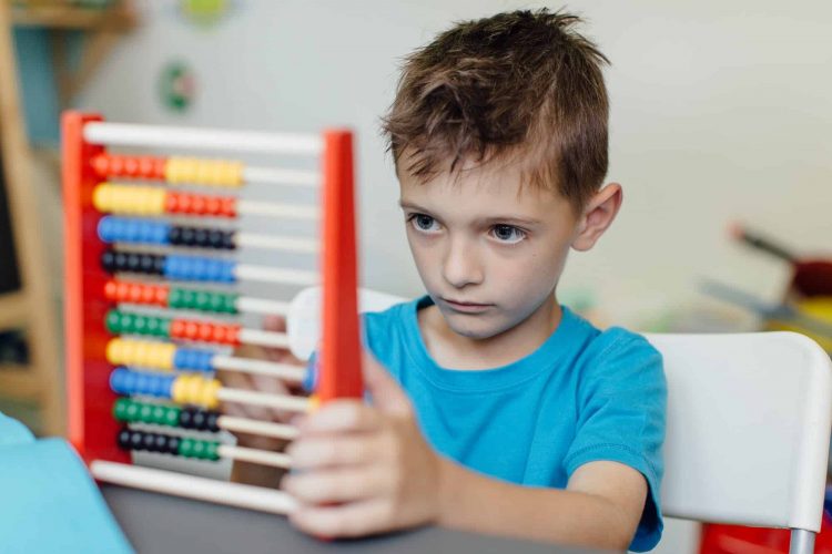 Focused schoolboy learning maths with an abacus