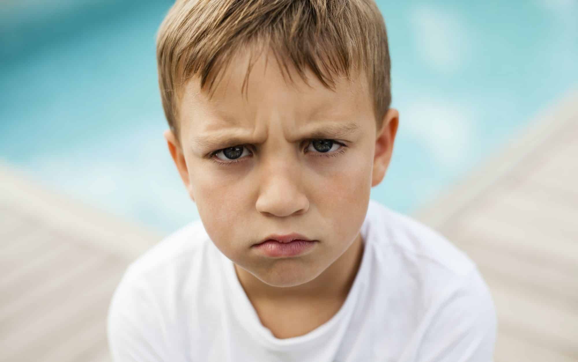 Portrait of angry boy against swimming pool