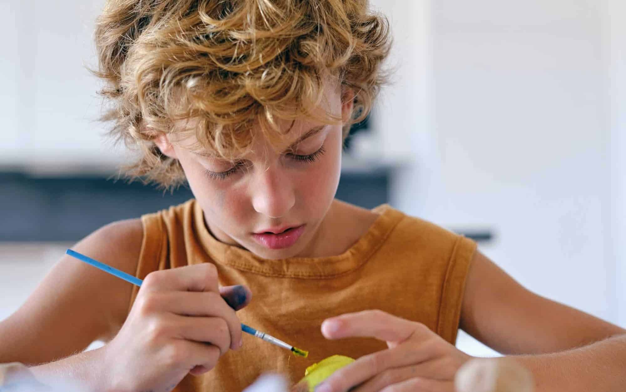 Focused child painting rock at home