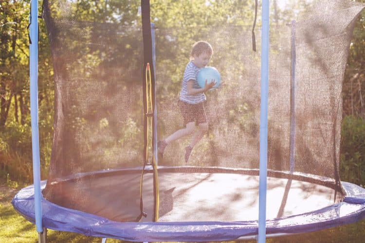 boy jumping on trampoline. child playing with a ball on a trampoline
