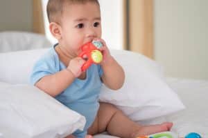 Cute newborn baby with toys in a bedroom.
