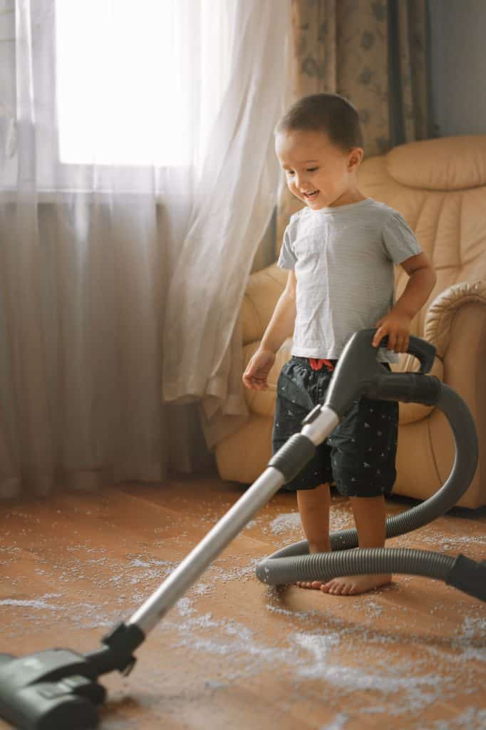 little boy 2-3 years old vacuuming the floor. child cleans up the house
