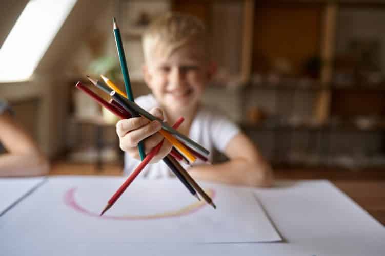 Little boy drawing with pencils, kid in workshop