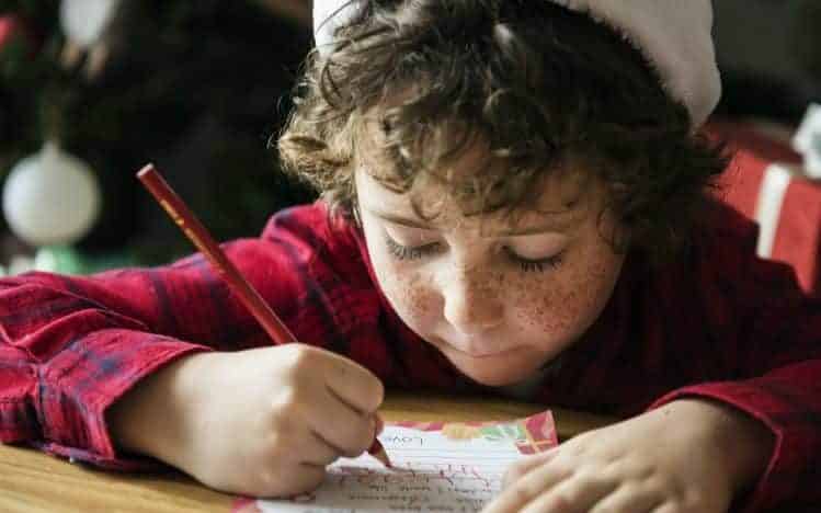 Caucasian kid writing a Christmas wishlist