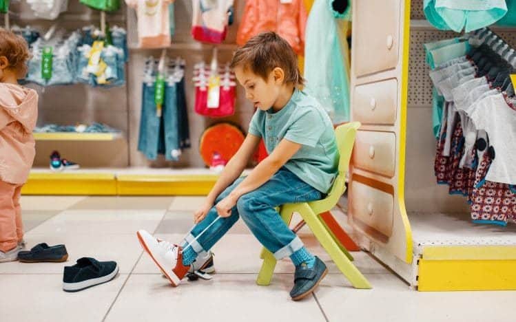 Little boy trying on shoes in kids store