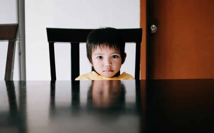 Image of young kid staring at you with reflection her face on table
