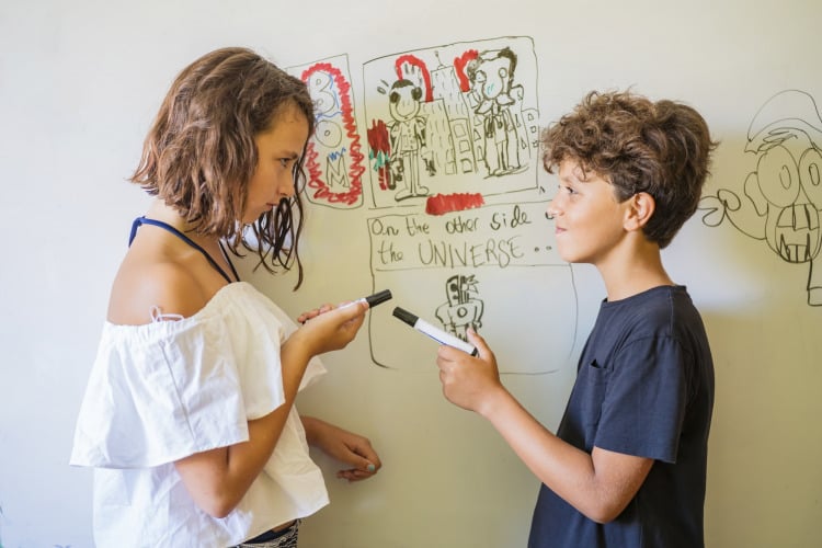 Girl and boy drawing on a whiteboard