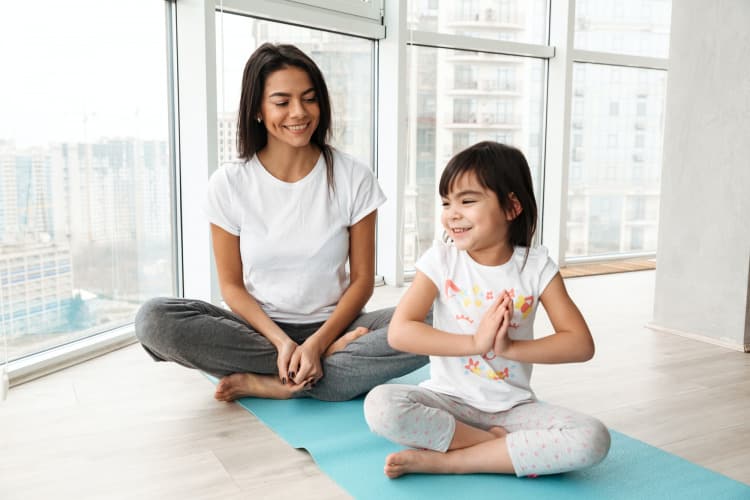 Happy people woman and little kid practicing yoga indoor, sittin