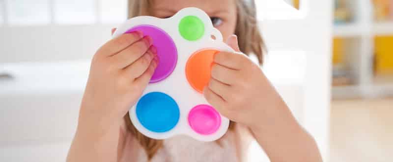 Little girl,kid,child plays with colorful pop it children's room, bedroom.Funny trendy silicone anti