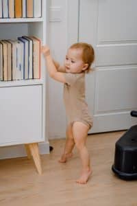 A cute baby learning to stand up or walking with support. First steps. Standing on toes abnormally.