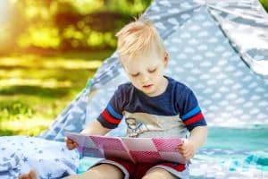 A little kid reads a book in the park. Boy preschool. The concep