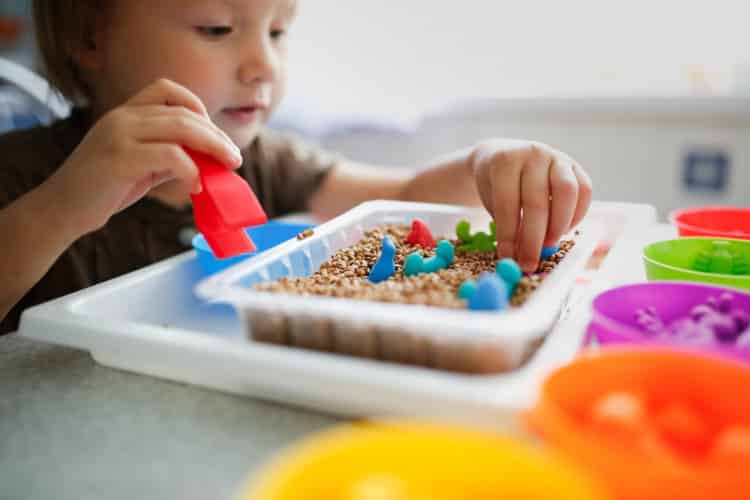 Baby Toddler plays with cereals, sorts toy figures by color. Child plays with tweezers