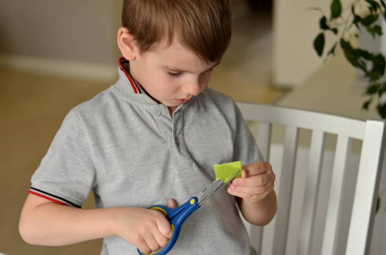boy cuts paper crafts with scissors