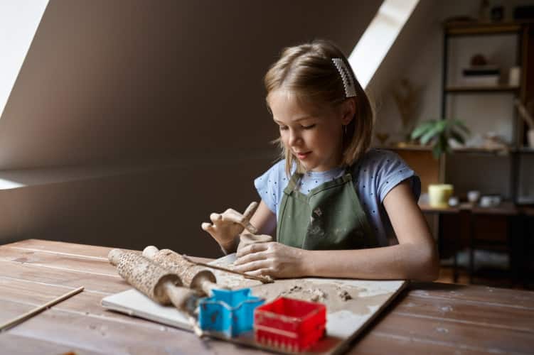 Little girl works with clay, kid in workshop