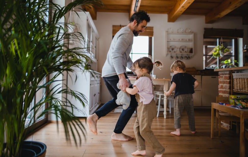 Mature father with two small children dancing indoors at home