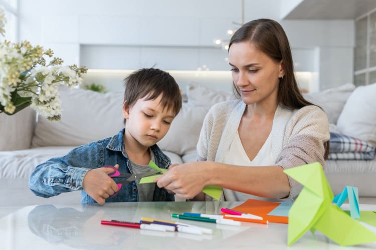 Mother and son cutting colored paper with scissors