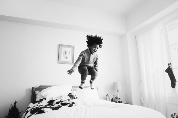 African kid having a fun time jumping on a bed