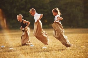 Jumping sack race outdoors in the field. Kids have fun at sunny daytime